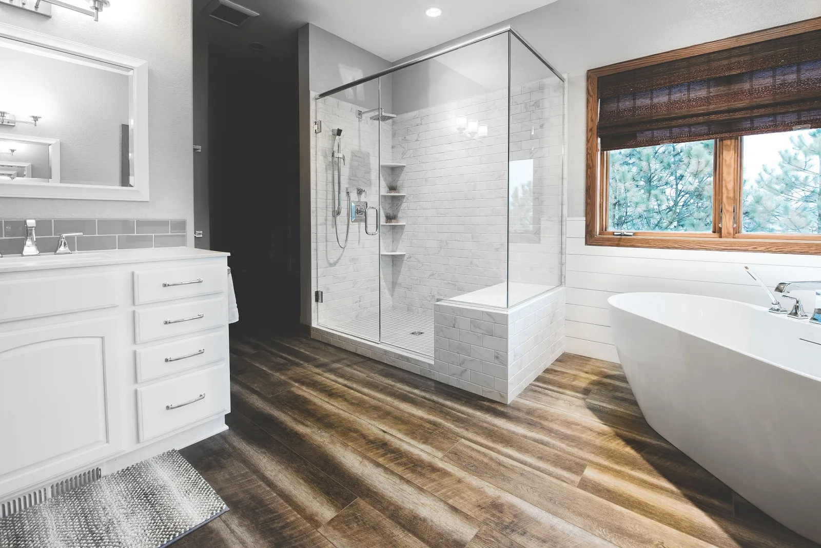 Finished bathroom with a glass shower, freestanding tub and wood-look floor