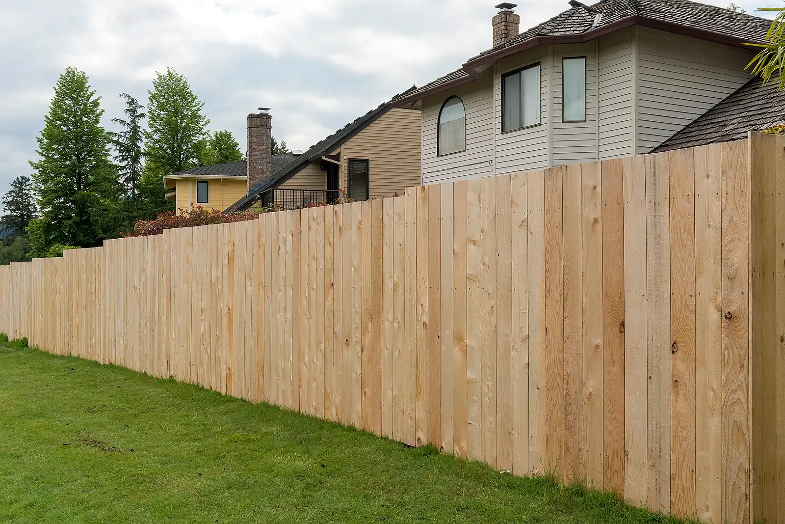 Newly installed wood privacy fence running along the side of a house