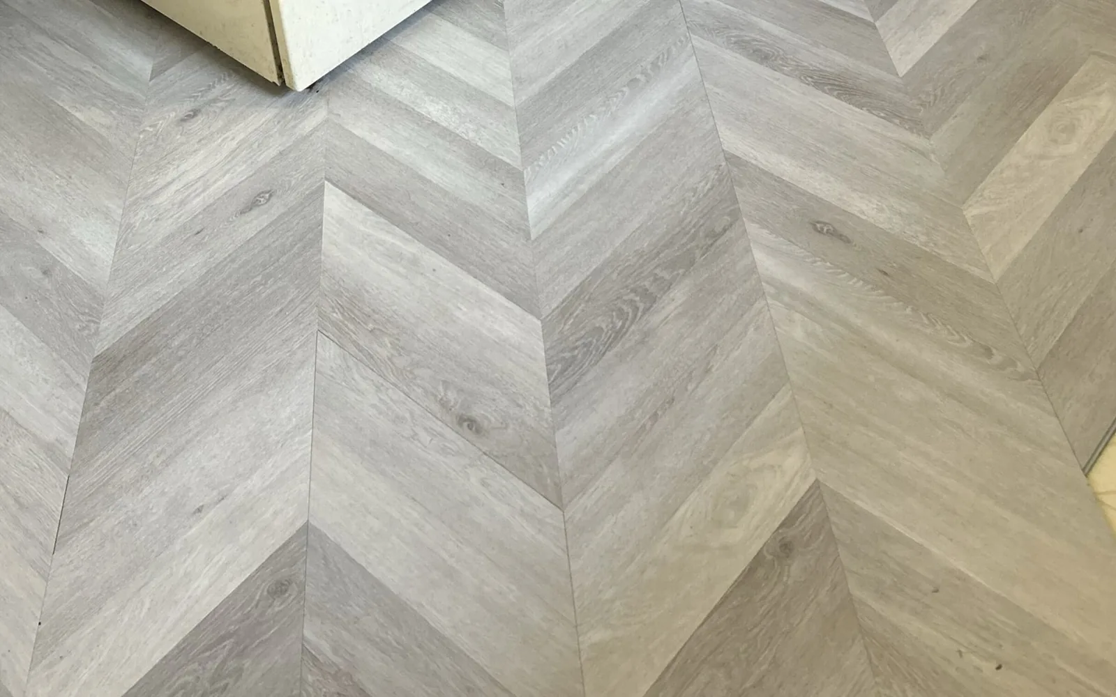 Finished chevron luxury vinyl plank floor meeting an old tile floor at a kitchen doorway