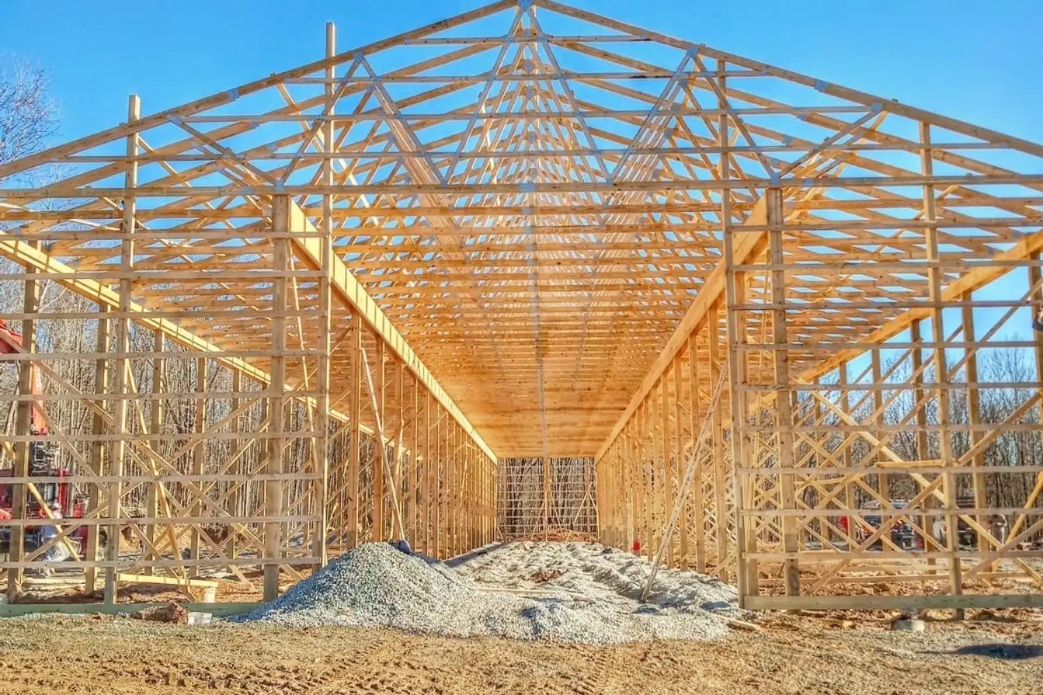 Post-frame pole barn shell with roof trusses set and open walls