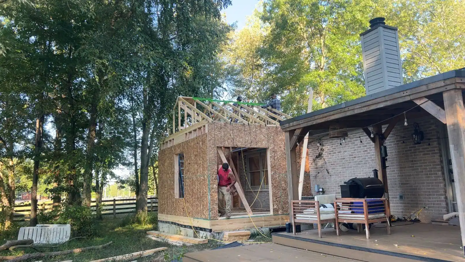 Sheathed addition being framed onto the side of an existing brick house