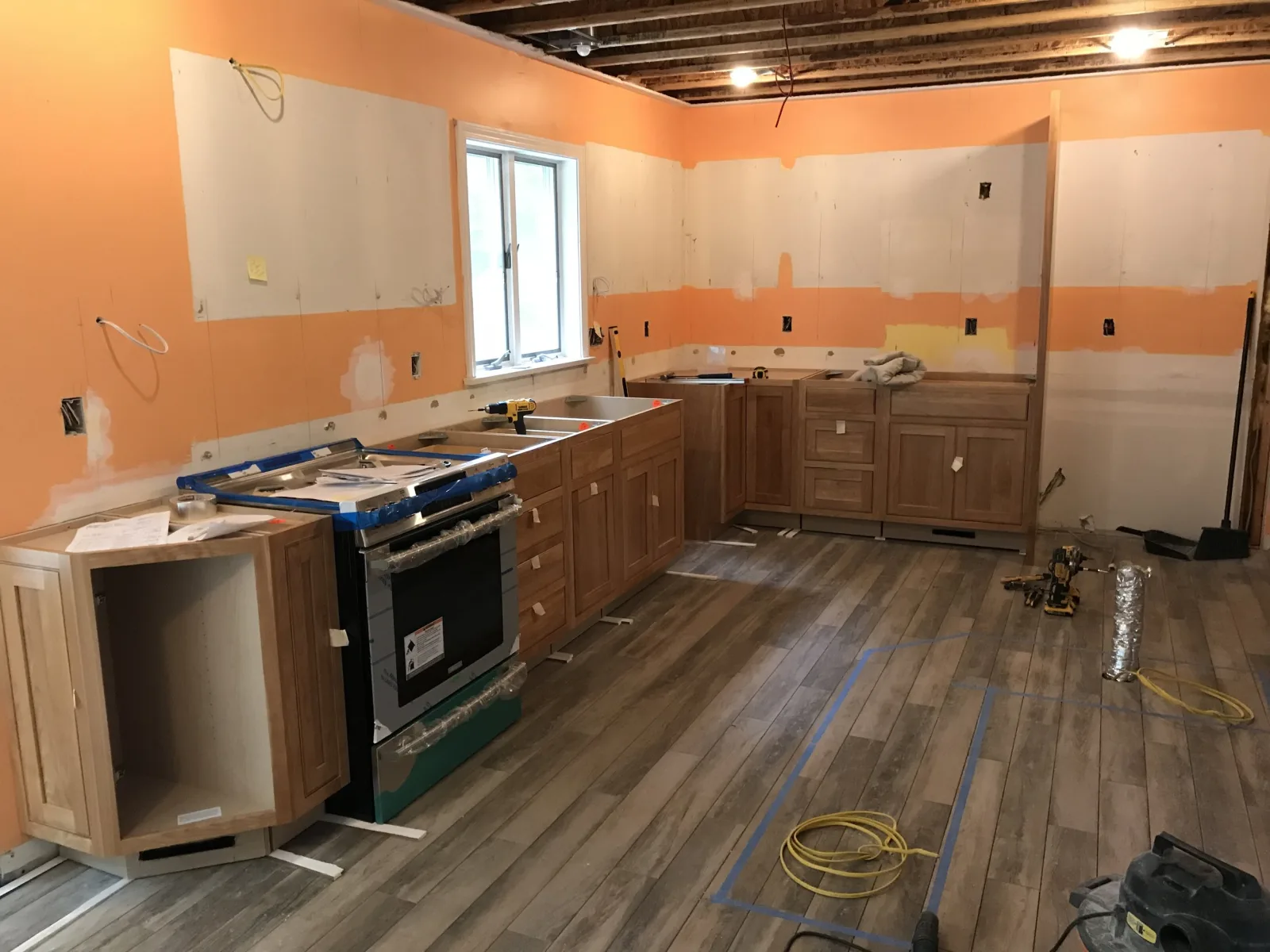 Kitchen mid-remodel with new cabinets set, shims in place and a drill on the counter