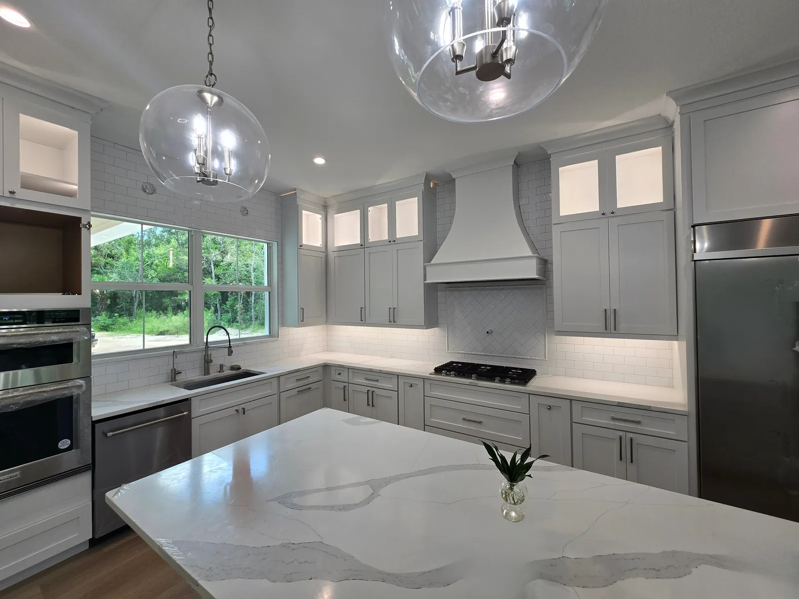 Remodeled kitchen with gray cabinets, a subway tile backsplash and a stone island