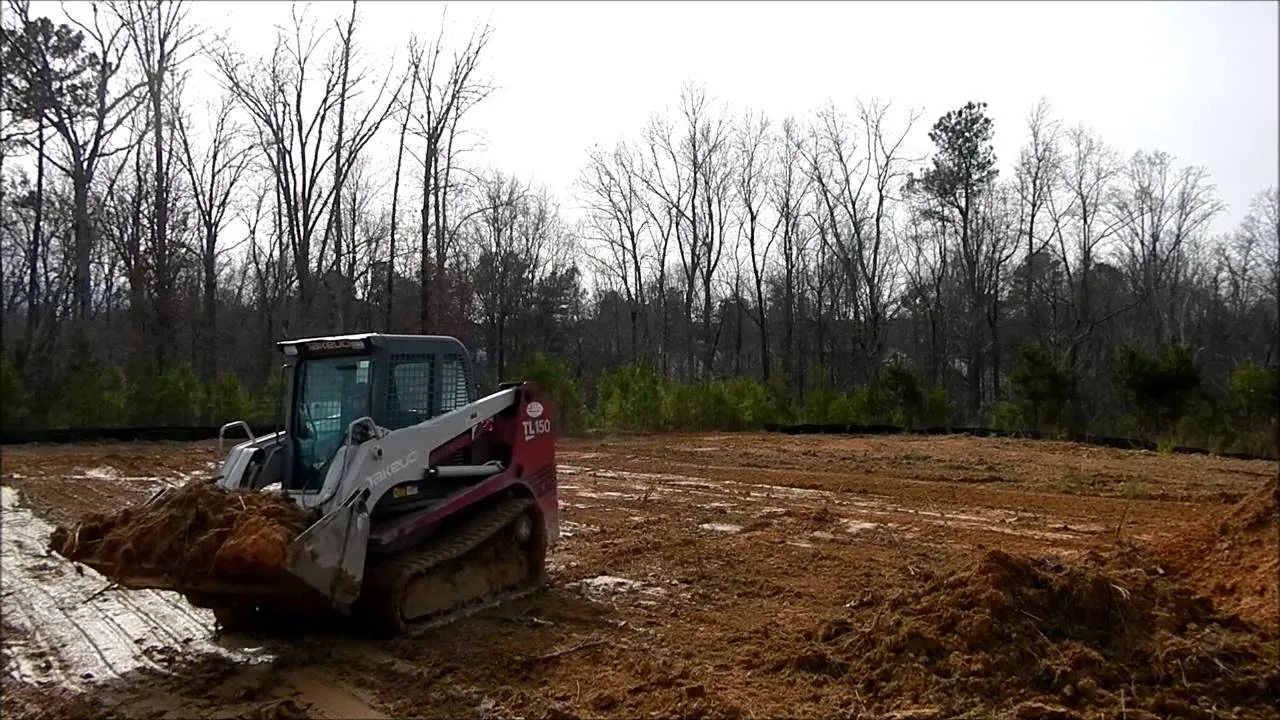 Compact track loader pushing fill across a graded building site