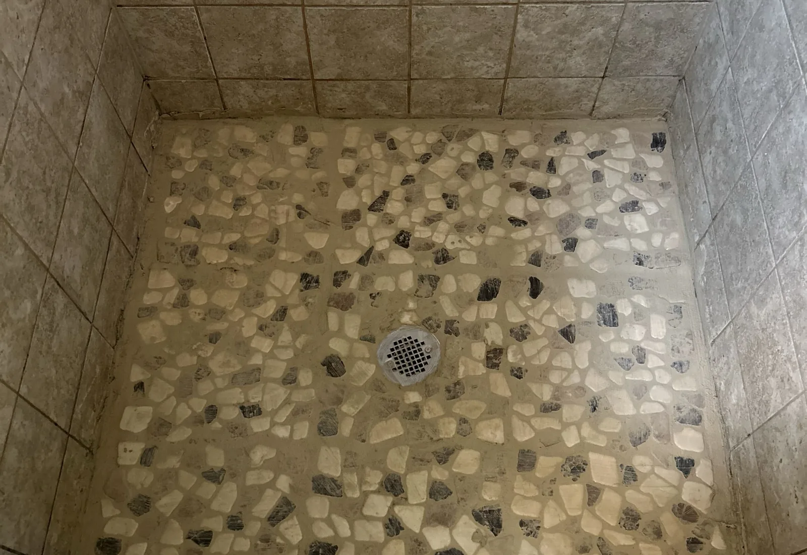 Finished pebble tile shower floor with a round center drain